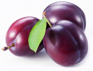 Three plums with leaves on white background.